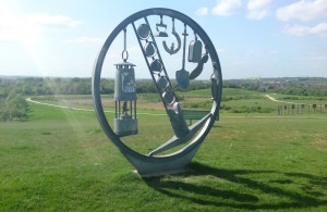 Circular metal sculpture comprised of farming, industrial and mining equipment